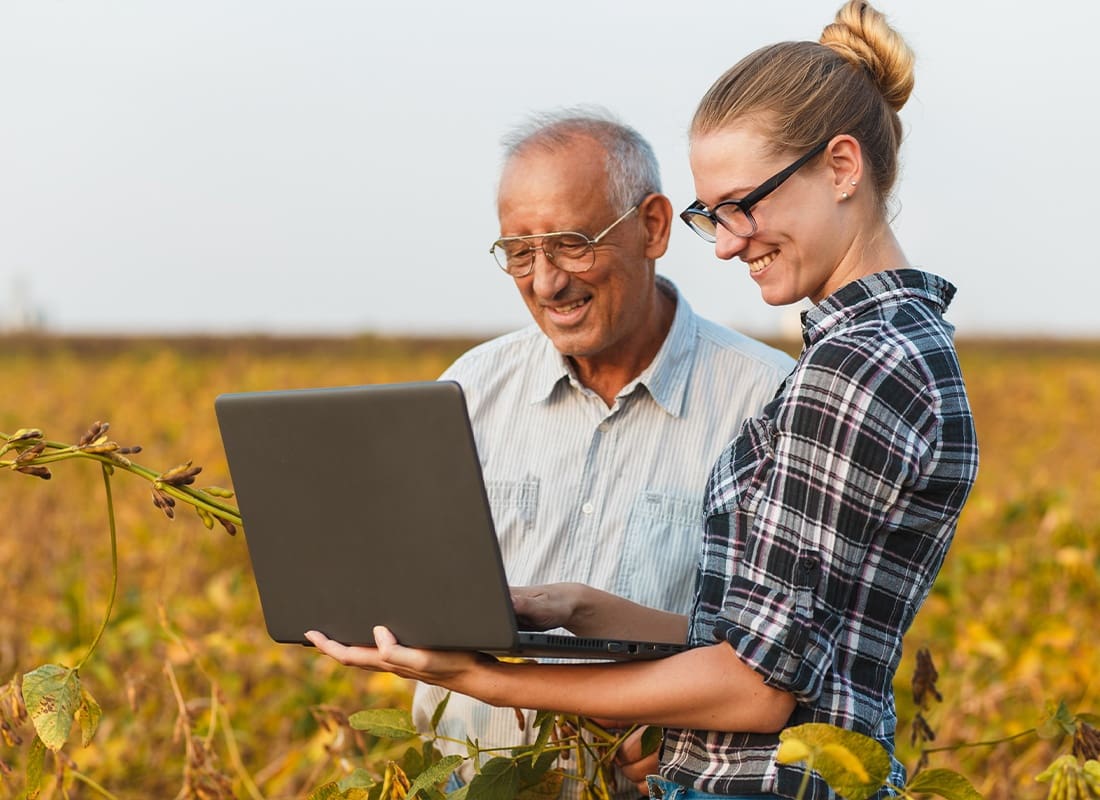 Arleens Accounting - Senior Male and Young Female Farmer With Laptop Standing in a Field Examining Soybean Crops